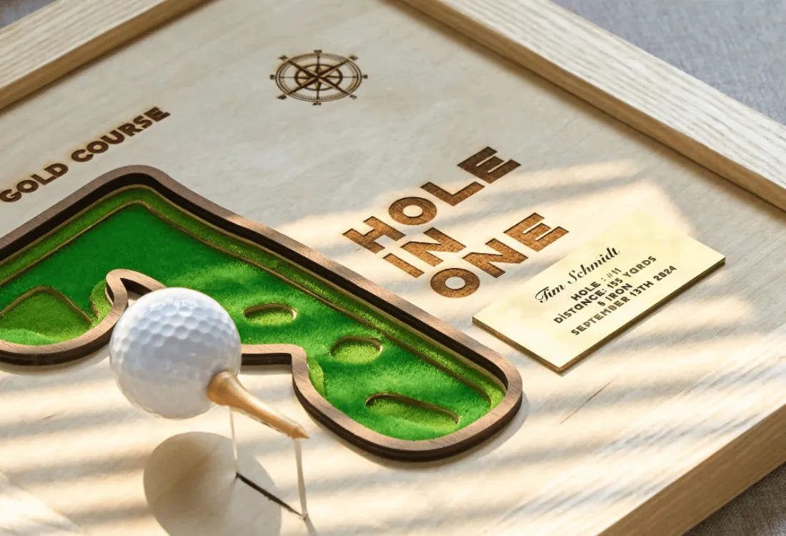Golf-themed decorative item with 'Hole in One' plaque and golf ball on a wooden surface.